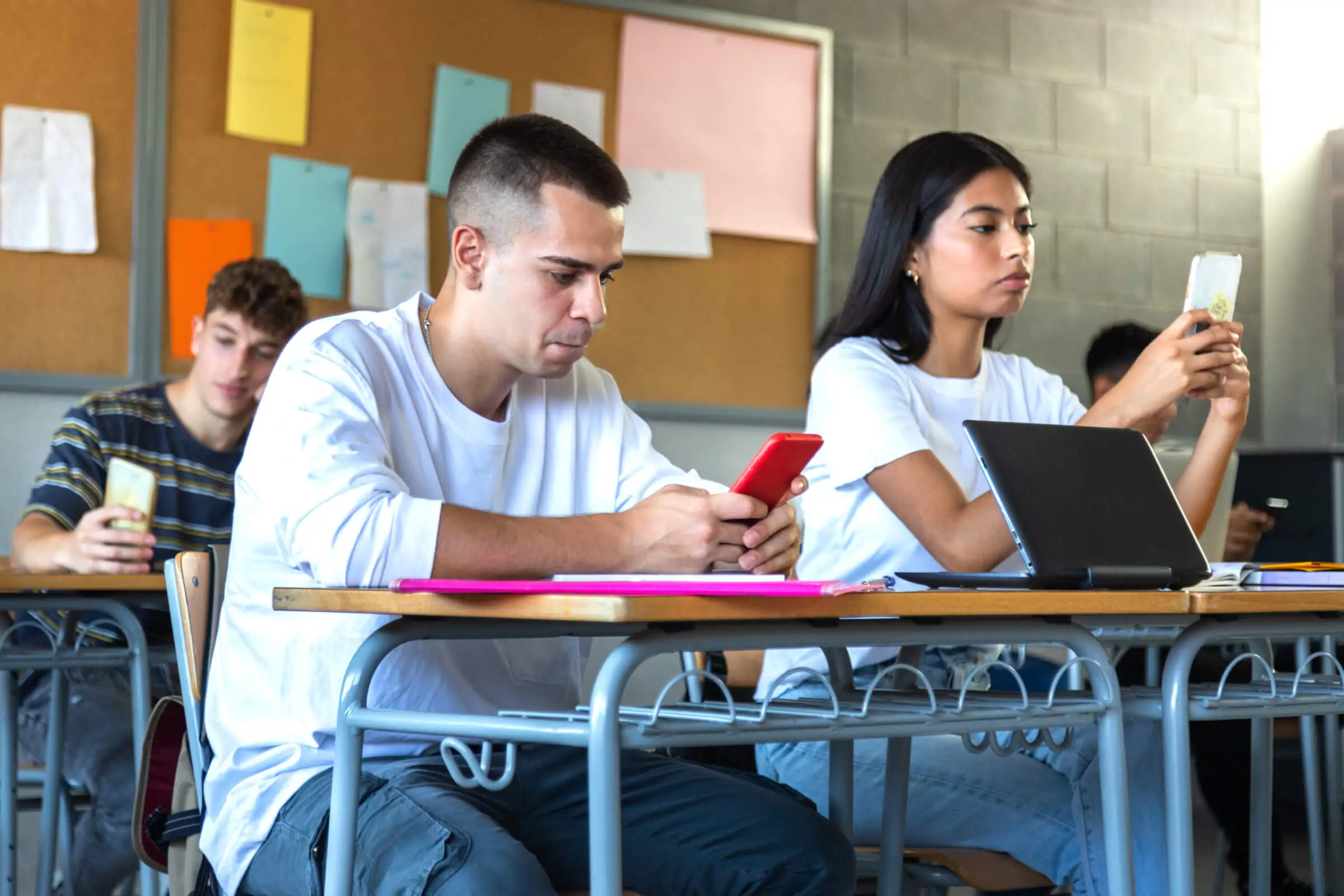 Students look at mobile phones in a classroom.