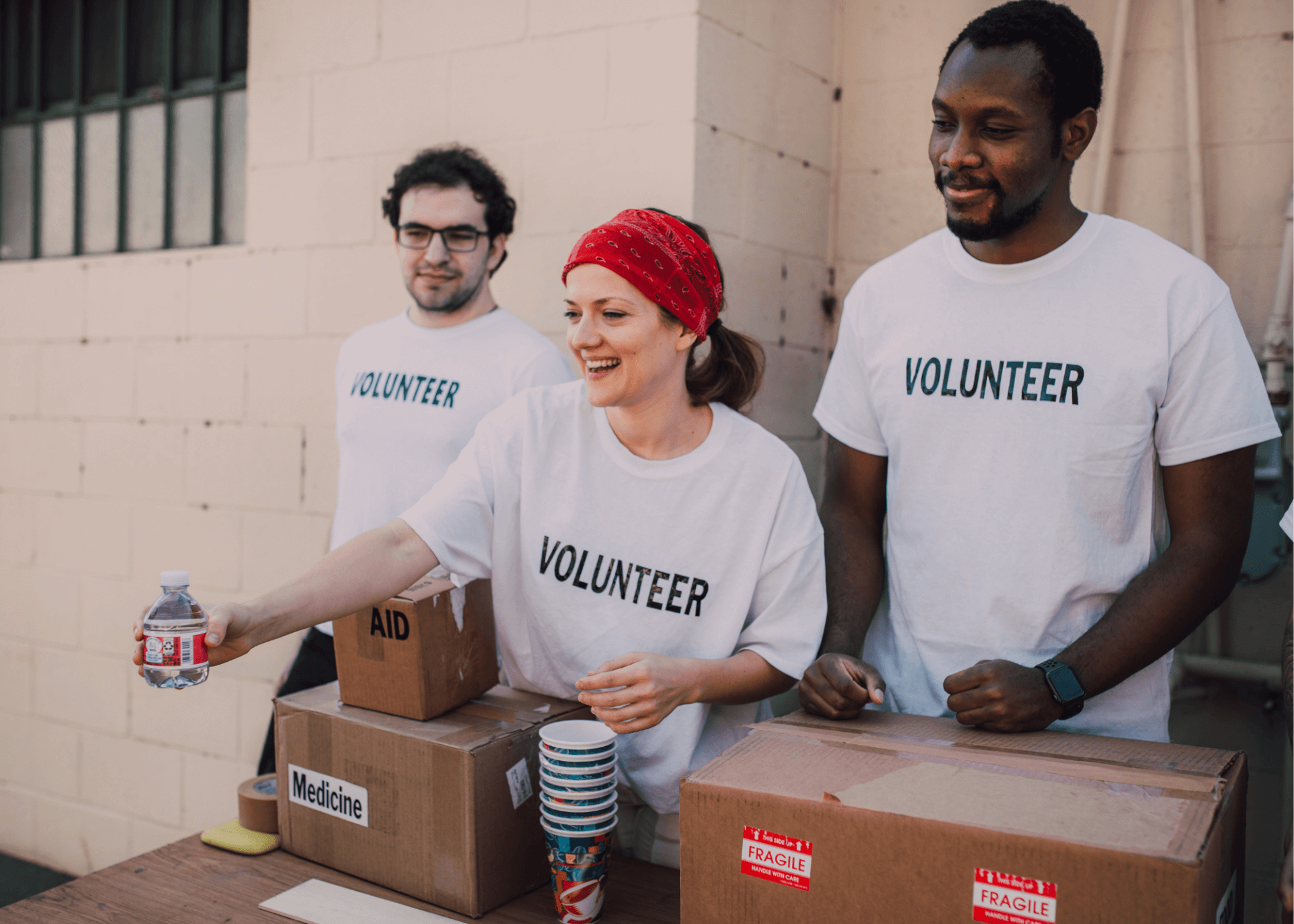 A group of three volunteers handing out bottled water.