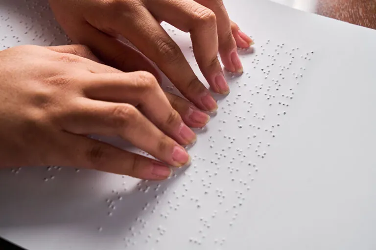 Woman reading braille with two hands.