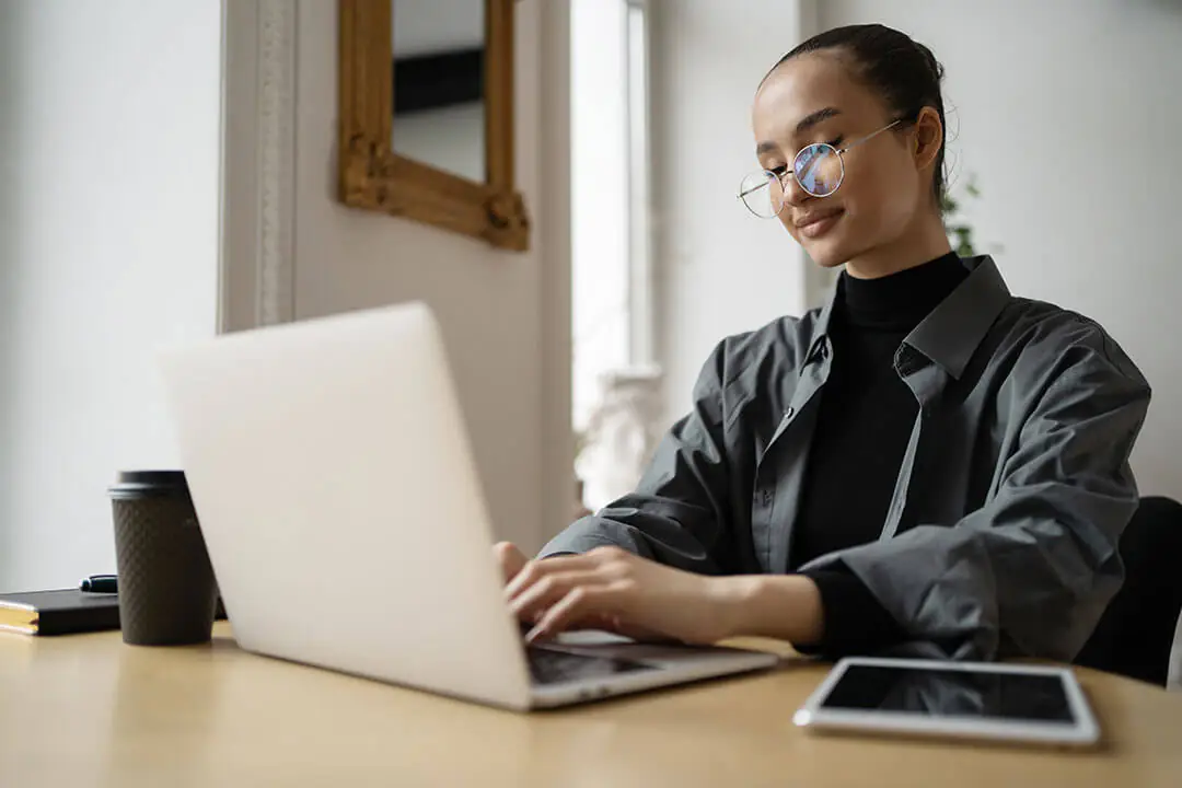 A woman working at a laptop computer on her desk.