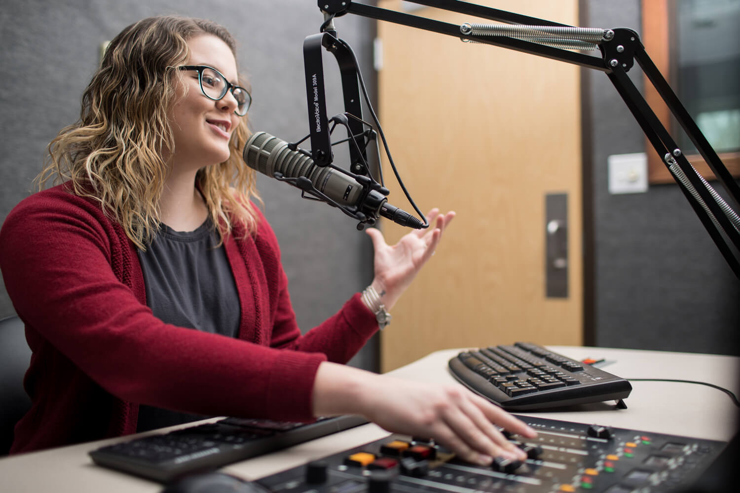 A woman in a radio studio speaking into a microphone.