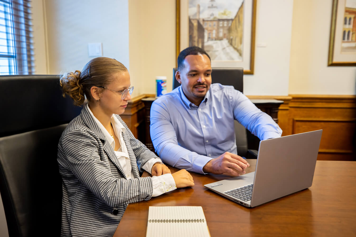 A man and woman sitting at a table with a laptop.