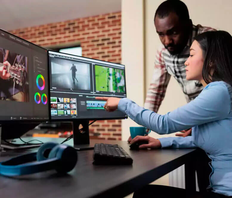 Man assisting a woman at a computer workstation