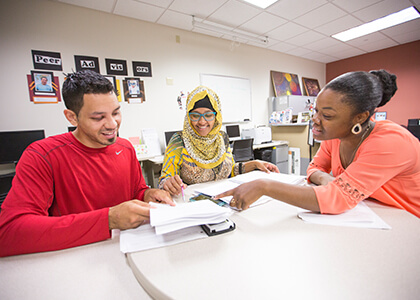 Three students collaborating on a project in a modern office setting.