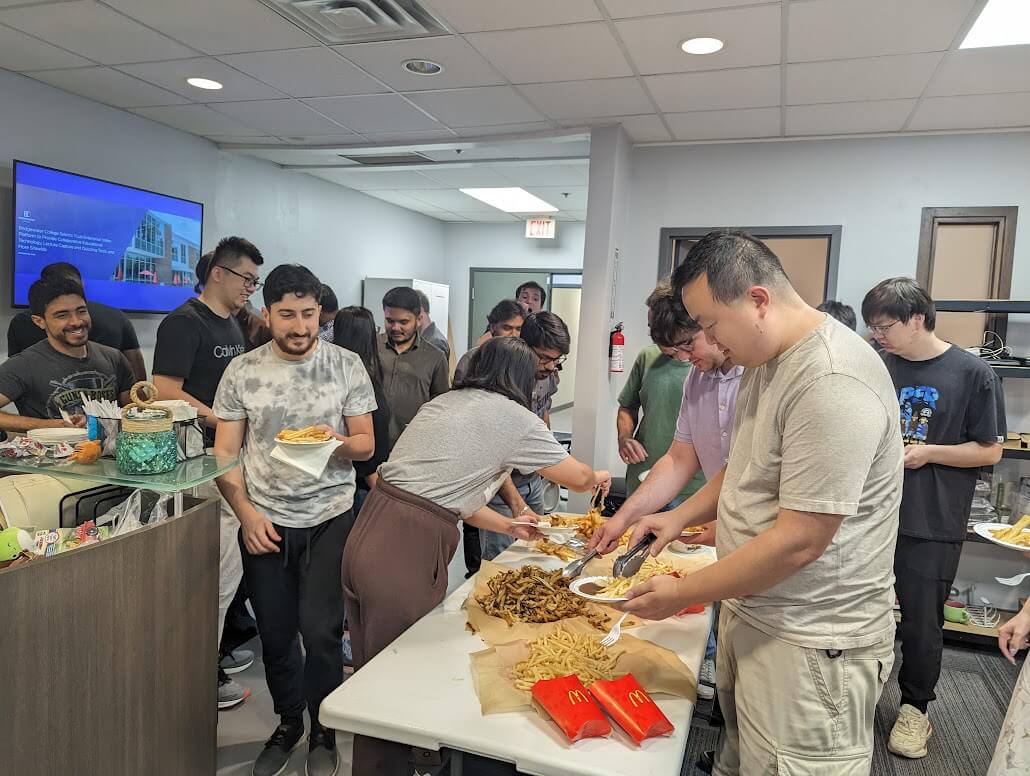 A group of people from the YuJa team standing around a table with food.