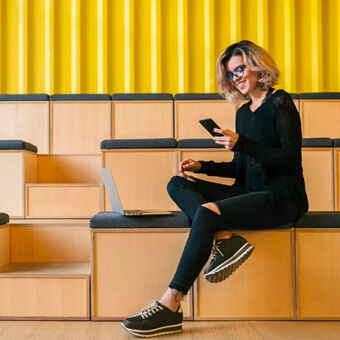 A woman sitting on a bench, engrossed in her cell phone.