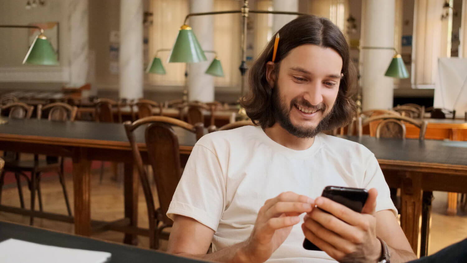 A bearded man with long hair sits at a table.